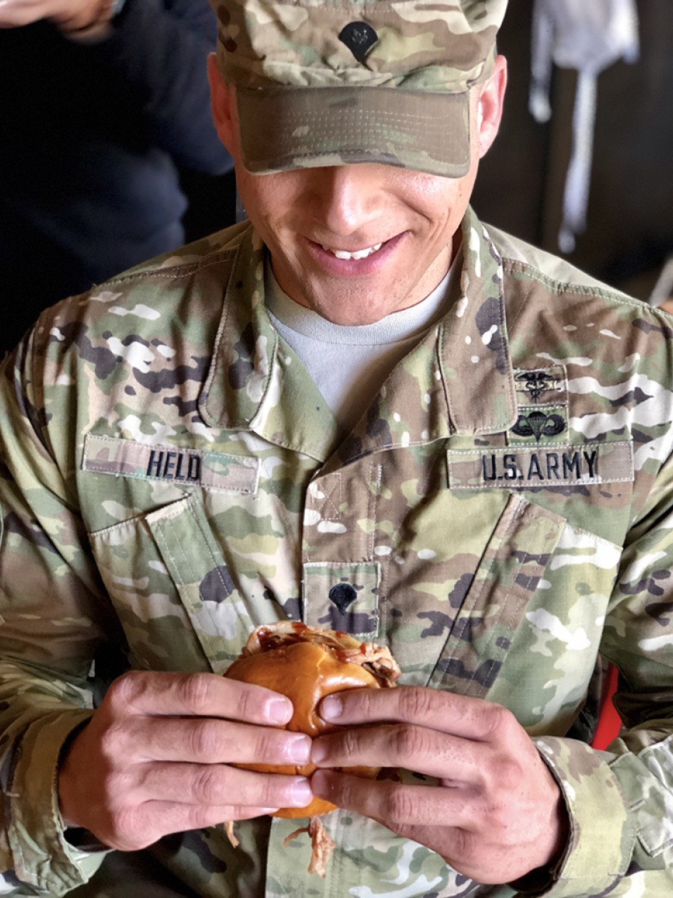 Uniformed soldier holding BBQ sandwich